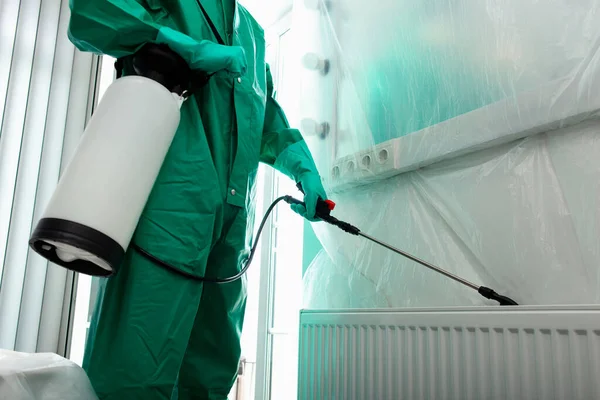 Homme en costume chimique se débarrasser des insectes derrière le radiateur photo de stock — Photo