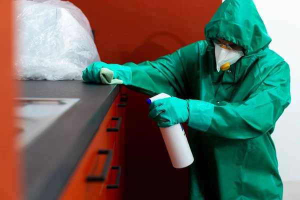 Homme en combinaison de protection pulvérisation de produits chimiques sur les armoires de cuisine — Photo
