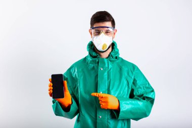 Maskeli ve gözlüklü bir adam modern akıllı telefon stok fotoğrafına bakıyor.