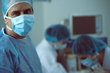 Olgun doktor, kadın asistanları ameliyat ediyor.