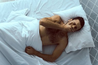 Genç çıplak adam evde uyanıyor.
