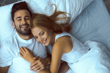 Mutlu eşler yatakta birbirini kucaklıyor.