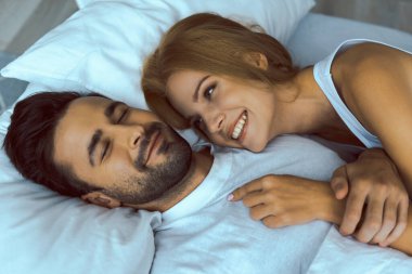 Sevgi dolu genç bir kadın erkeğin omzunda yatıyor.