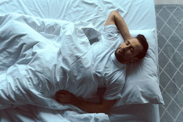 Sakin yakışıklı adam beyaz çarşaflarda uyuyor. — Stok fotoğraf