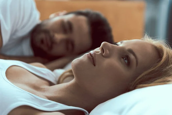 Спокойная женщина просыпается рядом с любимым мужчиной в постели — стоковое фото
