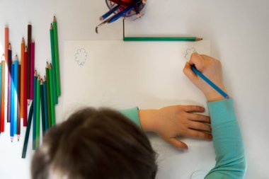 Küçük kız boş bir kağıt parçasına resim çiziyor.