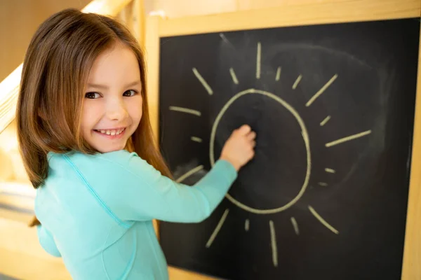 Menina alegre que desenha o sol no quadro — Fotografia de Stock