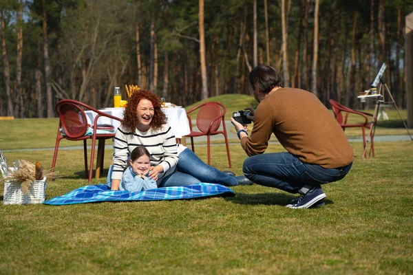 Hombre fotografiando a su encantadora esposa e hija durante el picnic —  Fotos de Stock