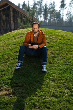 Dışarıda cep telefonu kullanan yakışıklı sakallı adam.