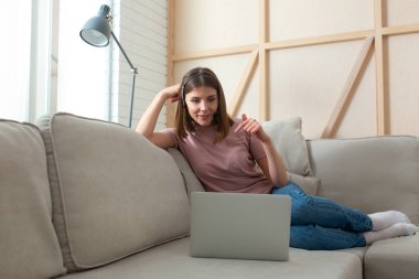 Güzel genç bayan evde dizüstü bilgisayar kullanıyor.