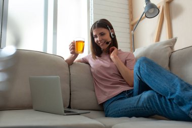 Mikrofonlu mutlu kadın internette dizüstü bilgisayarda çalışıyor.