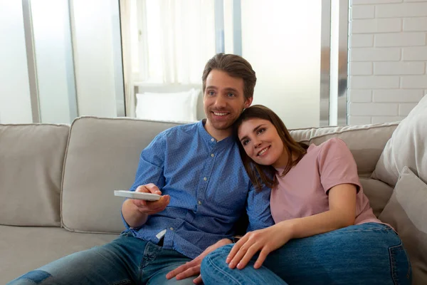 Pria dan wanita menonton TV dan duduk di sofa di kamar — Stok Foto