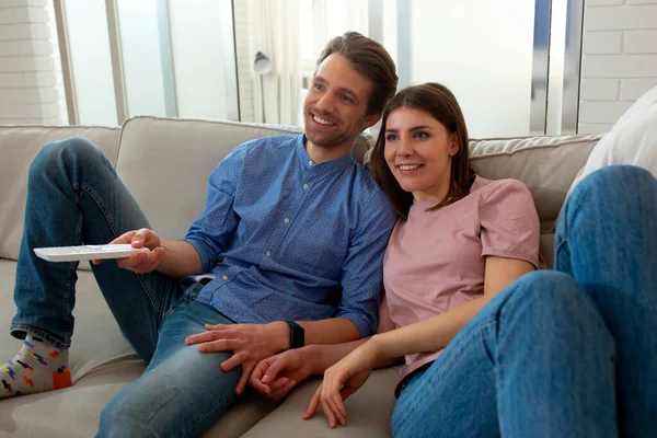 Gli sposi sorridenti stanno guardando la TV a casa — Foto Stock