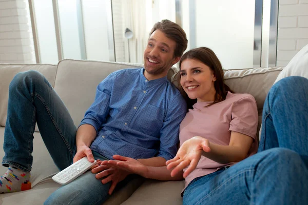 Partner sorridenti che guardano la TV e siedono sul divano — Foto Stock