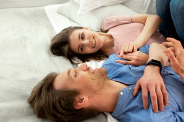 Genç ve gülümseyen bir çift evde birbirlerine sarılıyorlar.