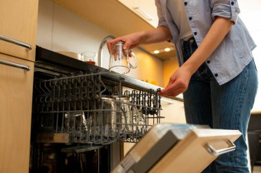 Tanınmayan bir kadın bulaşık makinesine bulaşık koyuyor.