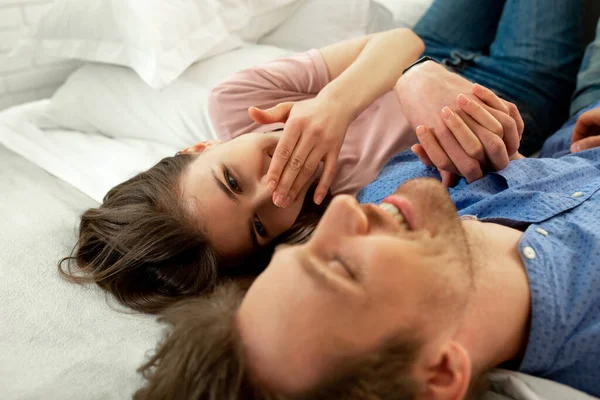 Joven pareja sonriente se relajan en la cama — Foto de Stock