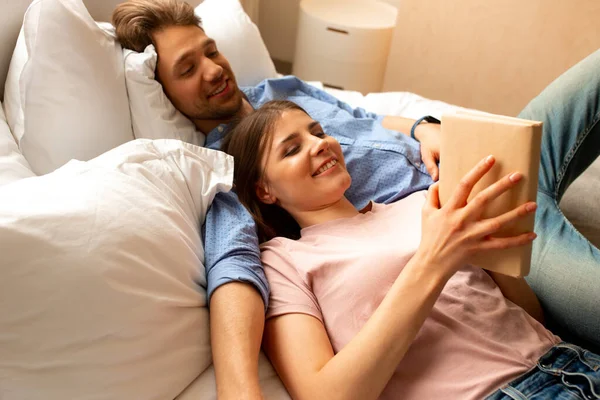 Joven pareja sonriente leyendo un libro en casa — Foto de Stock