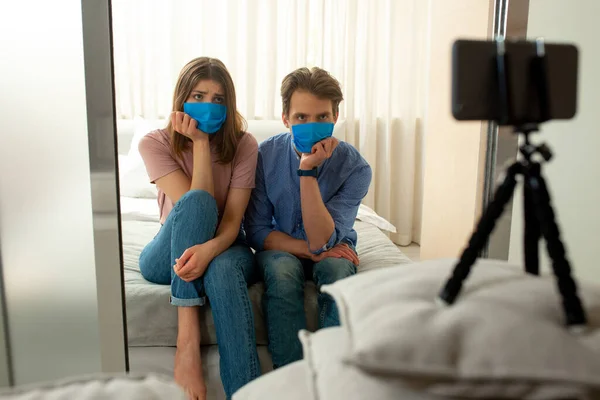 Mężczyzna i kobieta w niebieskich maskach podejmowania strzał przez telefon komórkowy — Zdjęcie stockowe