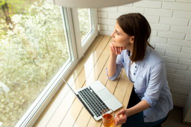 Genç bir kadın pencereye bakıyor.