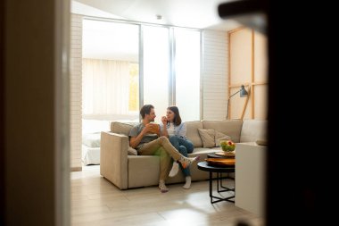 Oturma odasındaki kanepede oturan genç çift.