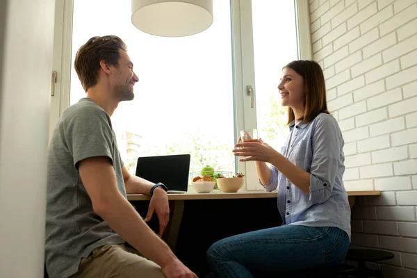 Uomo sorridente utilizzando laptop e bella donna godendo di tè — Foto Stock