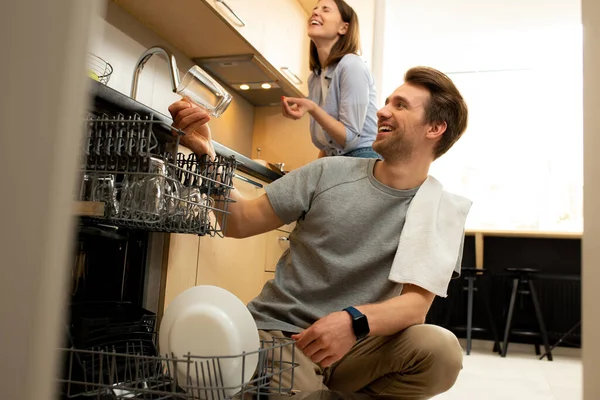 Lächelnder Mann holt Geschirr zu Hause aus der Spülmaschine — Stockfoto