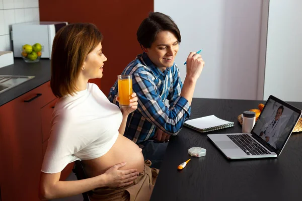 Casal alegre assistindo vídeo no laptop sobre a expectativa de bebê — Fotografia de Stock
