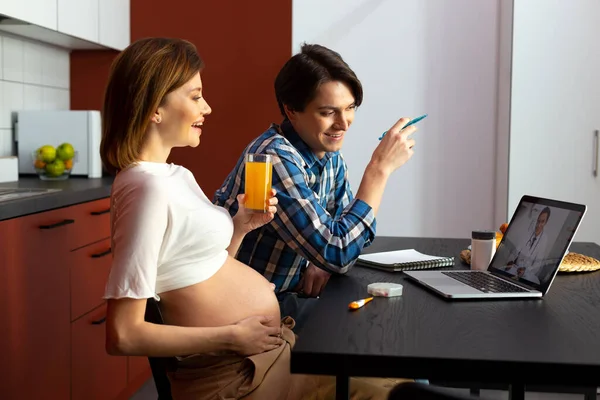 Fröhlich liebendes Paar schaut Video, während es ein Kind erwartet — Stockfoto