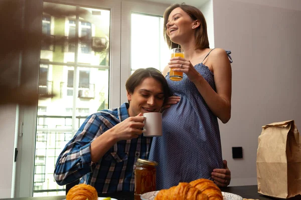 Futuros pais felizes desfrutando de bebidas na cozinha acolhedora — Fotografia de Stock