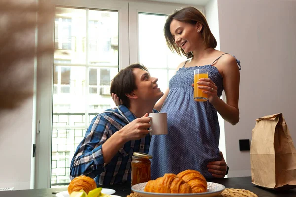 Fröhlicher junger Mann genießt Essen mit schwangerer Frau — Stockfoto