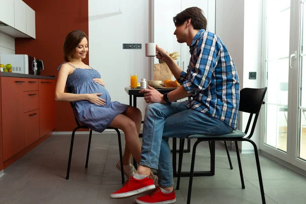 Lächelnder junger Mann frühstückt mit schwangerer Frau — Stockfoto
