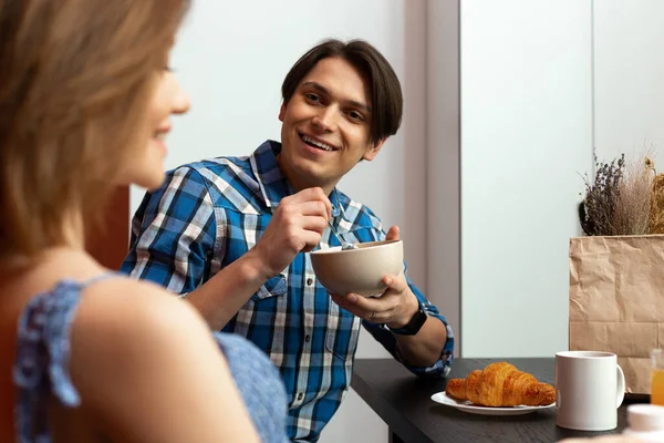 Щасливий чоловік розмовляє з жінкою під час сніданку на кухні — стокове фото