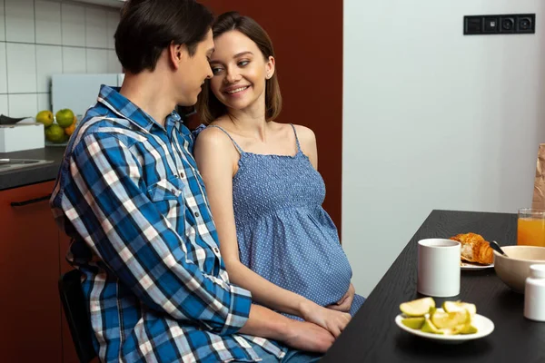 Fürsorglicher Mann umarmt schwangere Frau während des Essens — Stockfoto