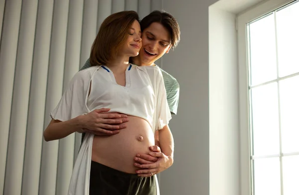 Heyecanlı genç adam bebek bekliyor ve karısına sarılıyor. — Stok fotoğraf