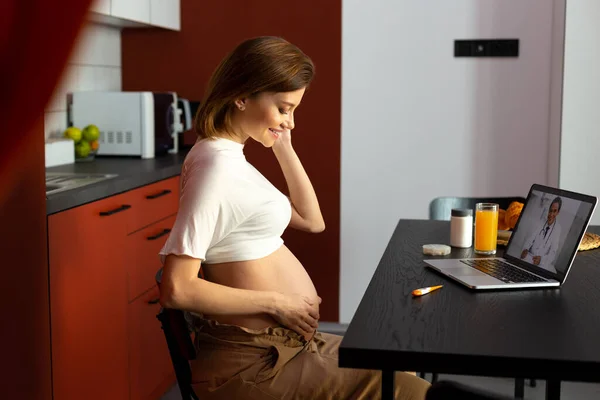 Gladsome terhes nő a videokonferencián orvossal — Stock Fotó