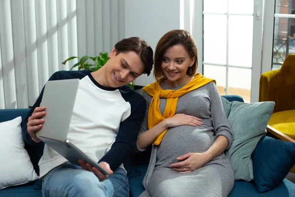 Счастливый мужчина показывает на камеру живот беременной жены — стоковое фото