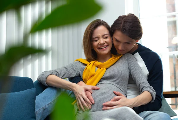 Zwangere vrouw lacht terwijl ze haar baby voelt duwen van binnen — Stockfoto