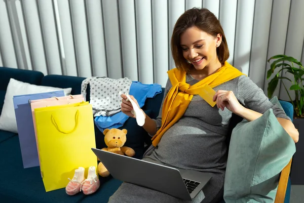 Senhora alegre com meias de bebê na frente da tela do laptop — Fotografia de Stock