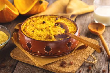 Darı püresi kabak ve ahşap arka plan üzerinde bir kil kase pişmiş kuru üzüm ile.