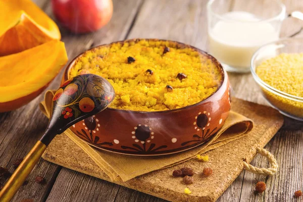 Darı püresi kabak ve ahşap arka plan üzerinde bir kil kase pişmiş kuru üzüm ile.