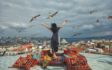 Happy girl on a rooftop with a view of Istanbul, Bosphorus and seagulls in a sky