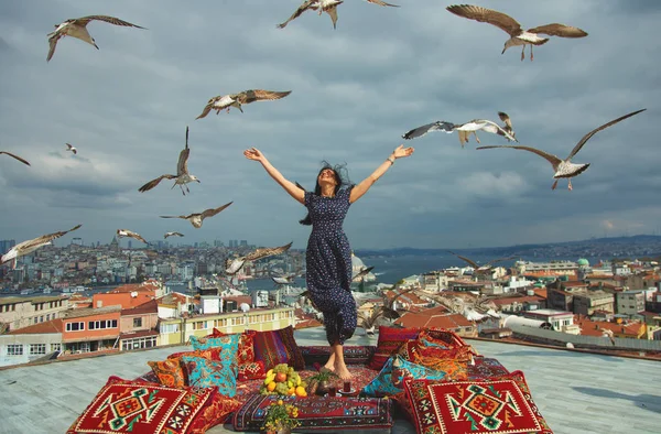 Happy girl on a rooftop with a view of Istanbul, Bosphorus and seagulls in a sky