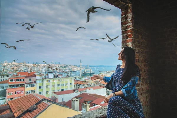 Happy girl at a window with view of Istanbul, Bosphorus and seagulls