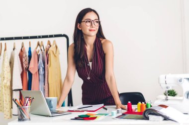Gülümseyen asya kadın moda tasarımcısı dizüstü bilgisayar ile çalışan
