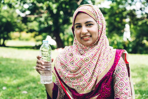 Portrait of happy arabic muslim woman with hijab dress drinking