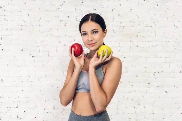 Αθλητισμός υγιή γυναίκα κρατώντας ένα κόκκινο μήλο απομονώνεται σε λευκό τοίχο β — Φωτογραφία Αρχείου