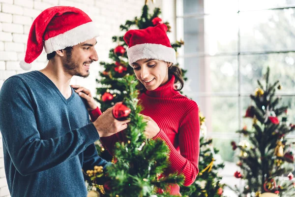 Casal doce romântico em chapéus de santa se divertindo decorando cristo — Fotografia de Stock