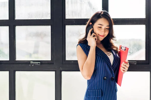 Femme d'affaires travaillant et utilisant le téléphone portable tout en se tenant dans o — Photo