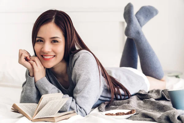 Jovem relaxante leitura livro na cama em casa — Fotografia de Stock